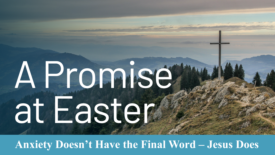 A large wooden cross stands on a rocky mountain ridge overlooking rolling hills and a cloudy sky. Text on the image reads: ‘A Promise at Easter.’ A banner below adds: ‘Anxiety Doesn’t Have the Final Word – Jesus Does.’