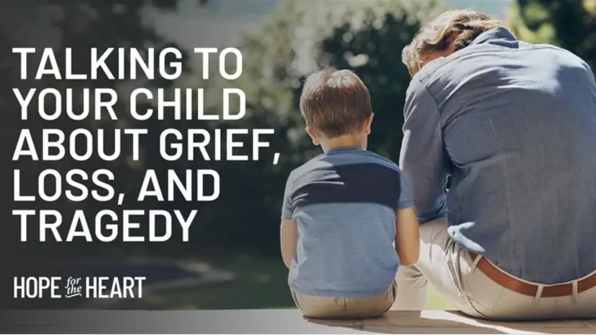 An adult and a young boy sit side by side outdoors on a ledge, both facing away as the adult leans forward in a posture of concern or reflection. Text on the image reads: ‘Talking to Your Child About Grief, Loss, and Tragedy.’ The Hope for the Heart logo appears below.